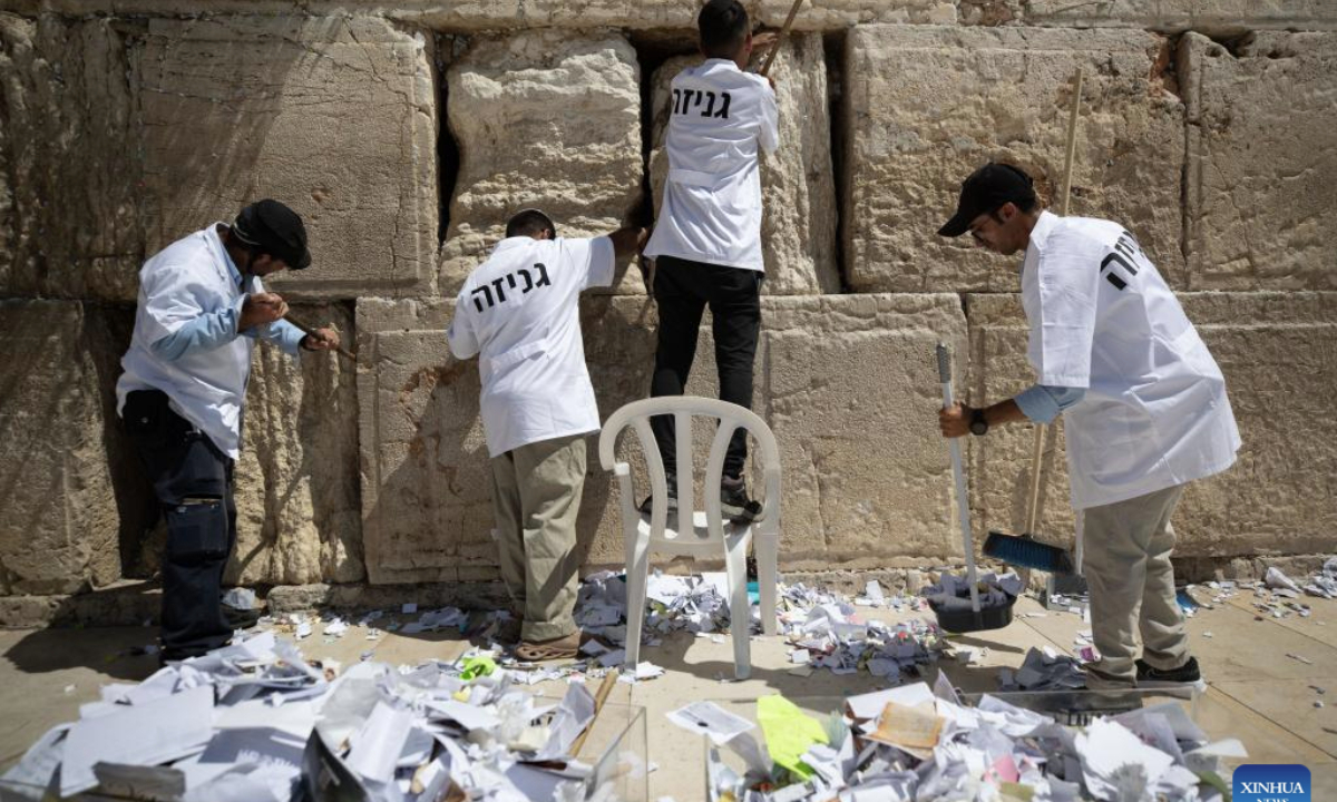 Staff members remove notes from cracks of Western Wall in Jerusalem's Old City