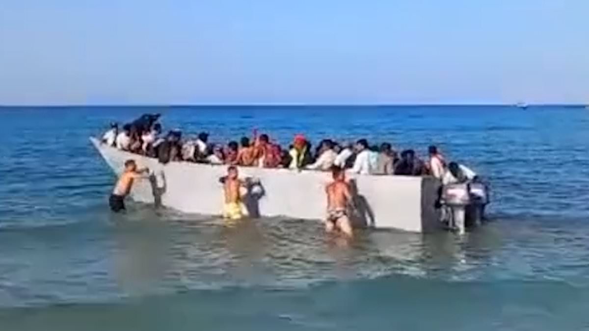 Tourists push boat packed with migrants away from shore