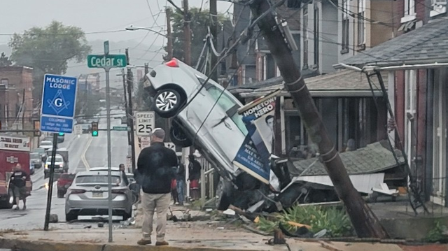 Woman hospitalized after car crashes into home, lands upright on wires