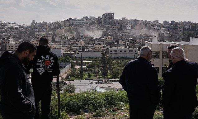 Palestinians watch as Israeli bulldozers claw down their West Bank...